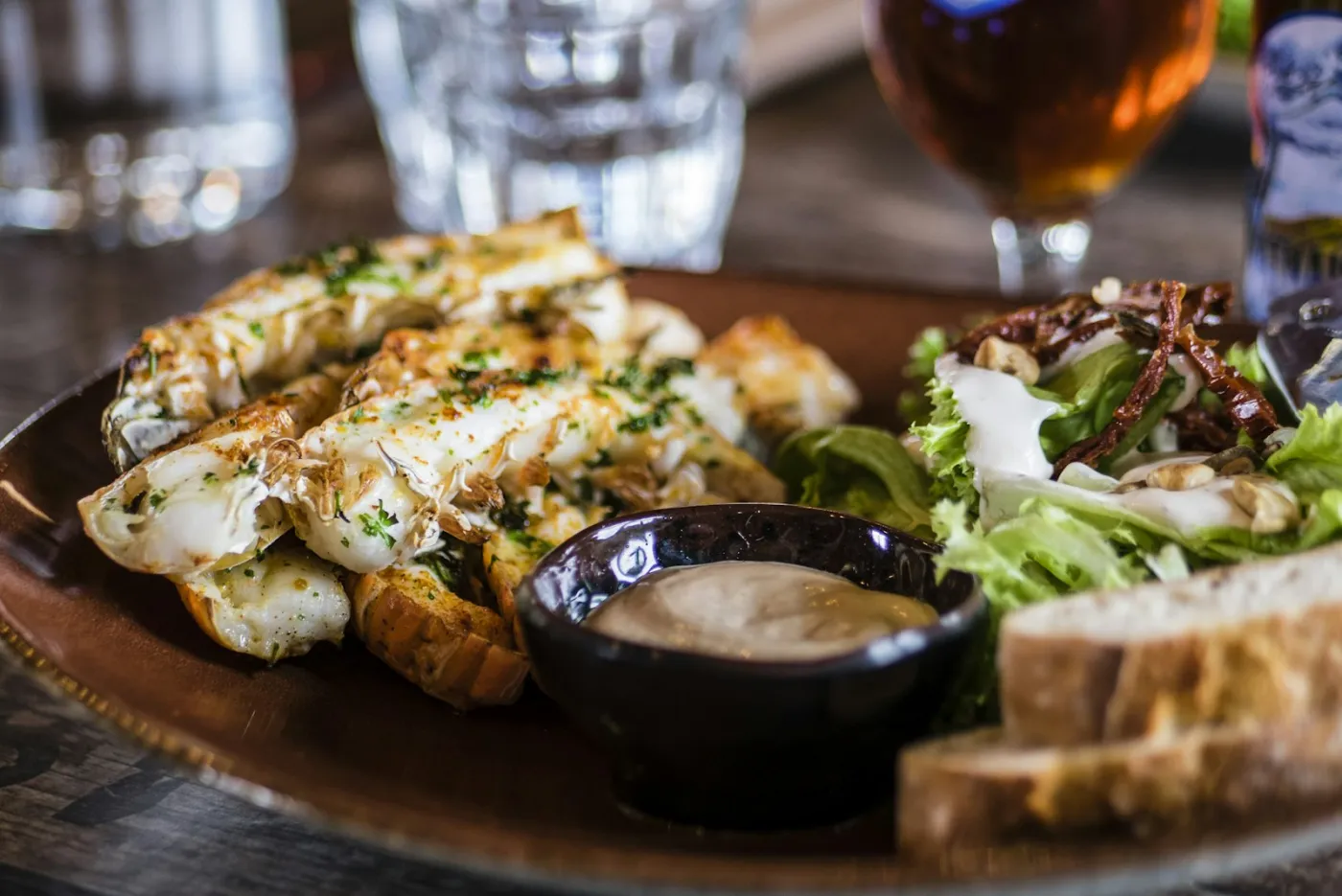 A plated fish dish with roast potatoes and greens on a dark table